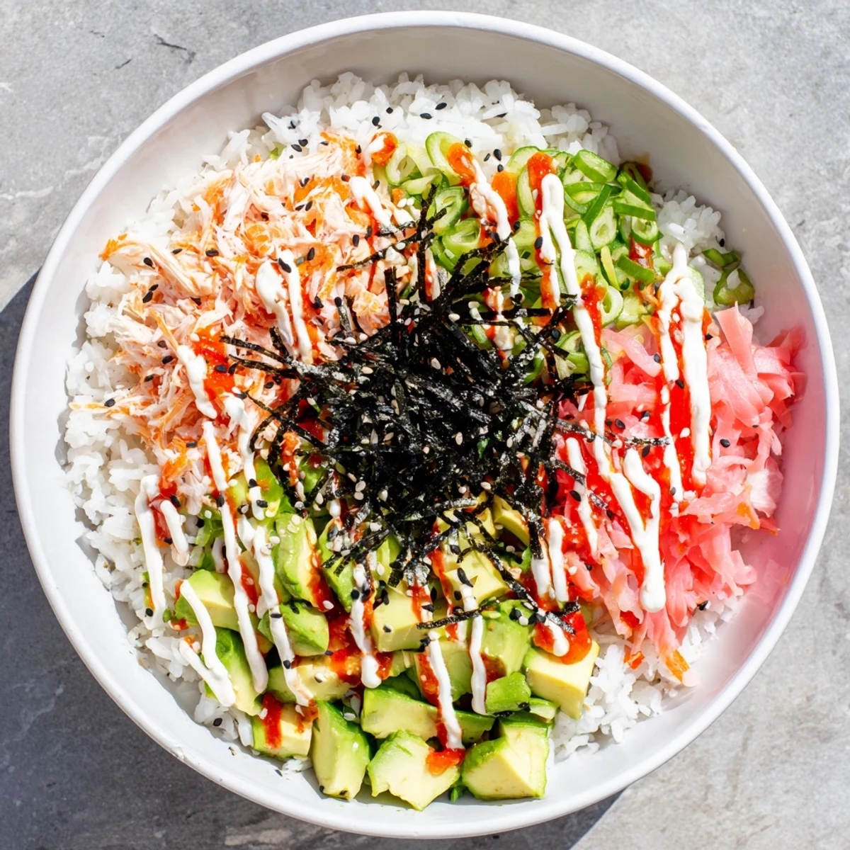Colorful California Roll Sushi Bowl with fluffy rice, crab, avocado, cucumber and spicy mayo drizzle