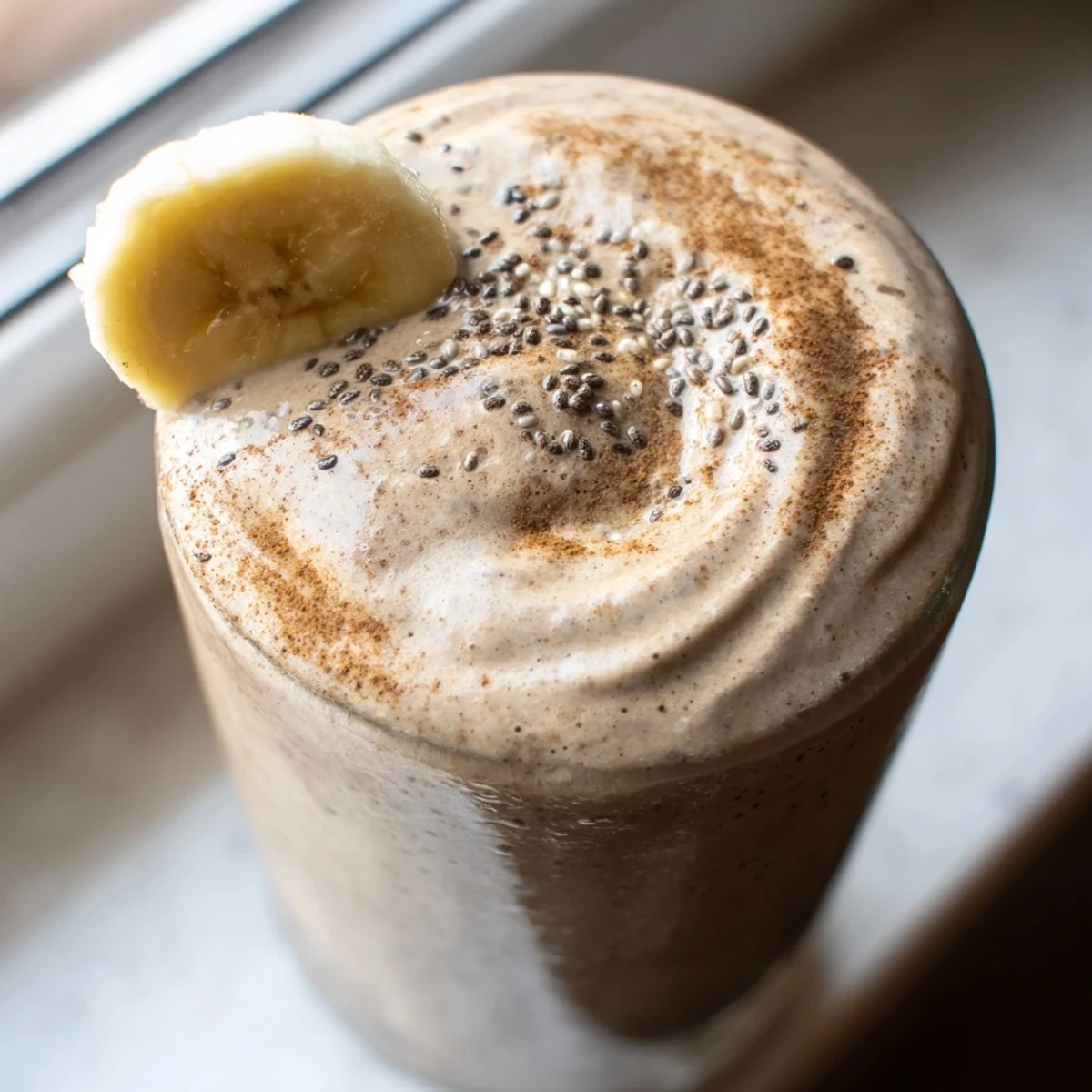 Thick frothy banana protein coffee smoothie poured over ice for morning energy