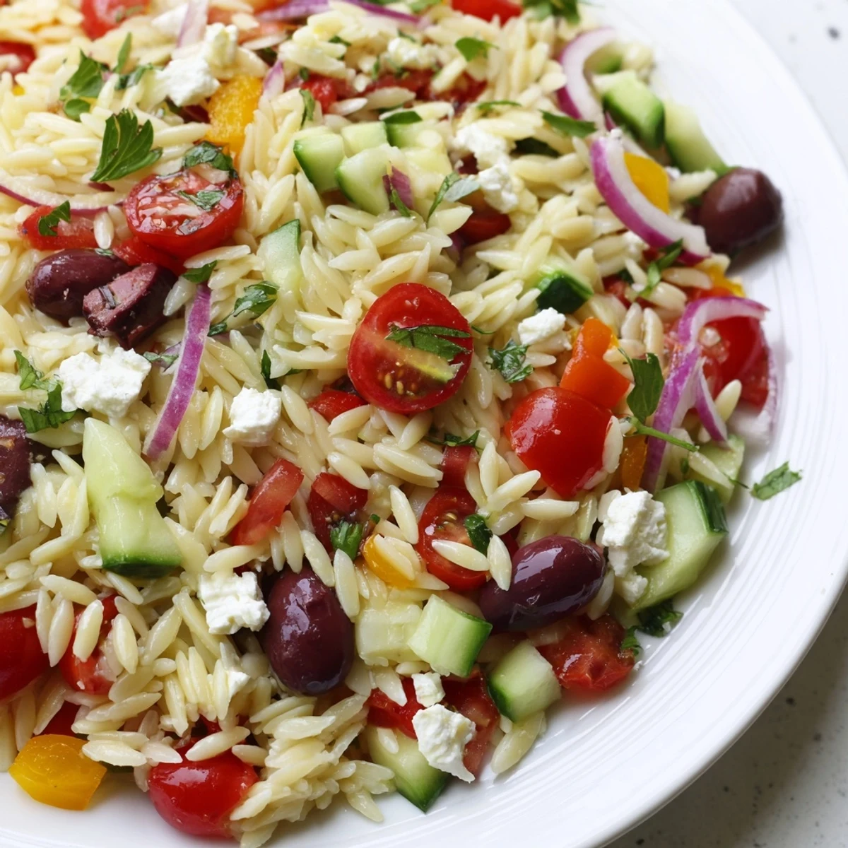 Close-up of Juicy Mediterranean Orzo Pasta Salad featuring plump tomatoes, cucumber, and tangy lemon dressing